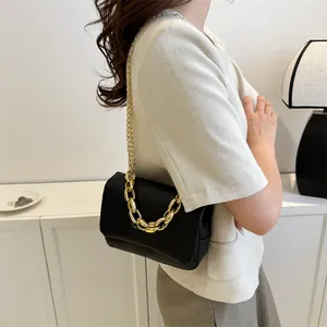 Détail du sac à main noir avec poignée en chaîne dorée et bandoulière en métal brillant