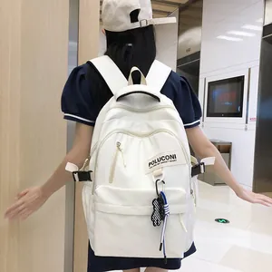 Sac à dos d'école blanc minimaliste avec pendentif ours porté par un mannequin