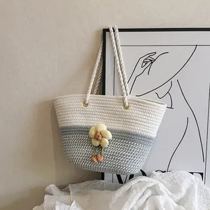 Détail d'un sac seau tissé avec pendentif fleur jaune et anses en corde épaisse