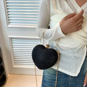Macro shot of a black heart-shaped evening bag with sparkling texture and gold handle