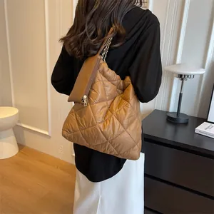 Detailed view of brown quilted tote bag with matching zipper pouch on metal chain