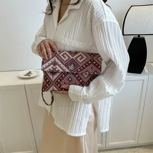 Retro ethnic woven envelope clutch with geometric diamond patterns and gold flower clasp