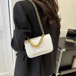 Sac à bandoulière carré blanc avec chaînes dorées porté par un mannequin