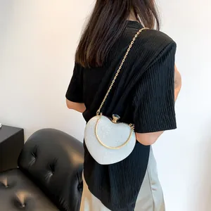 Silver glitter heart-shaped evening bag with gold chain strap shown on a model