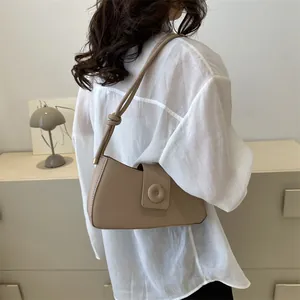 Minimalist beige baguette bag shown on shoulder with elegant knotted strap and round buckle