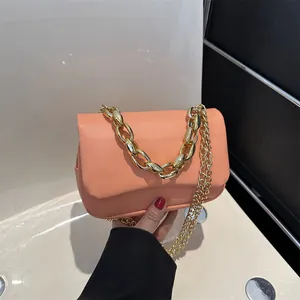 Détail d'un sac à bandoulière orange rose avec chaîne dorée et texture cuir PU