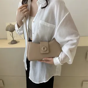Chic beige underarm bag with decorative ring detail styled on a model in a minimal setting