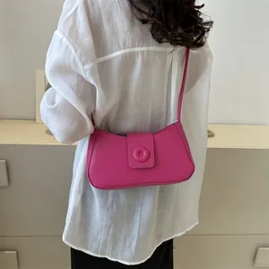 Detail of rose pink underarm bag with a smooth PU leather finish and circular buckle