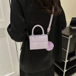 Detail of lavender quilted mini handbag with plush monster charm and adjustable strap