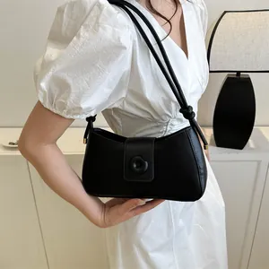 Detail of black faux leather underarm bag with knot strap on white dress model