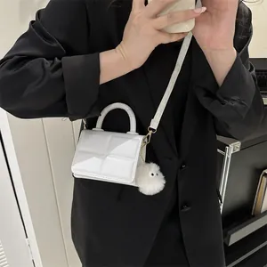 Lifestyle shot of a mini white plaid handbag with a decorative fur ball on a black blazer