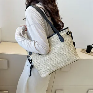 Dettaglio borsa tote in paglia intrecciata con finiture in pelle nera e nappe decorative