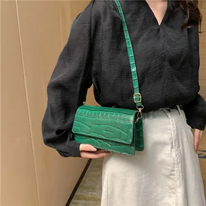 Detailansicht der grünen Krokodilledertasche mit goldenen Details und Seitenfalten