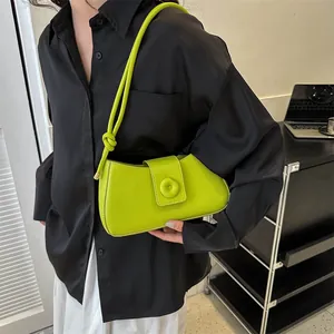 Detail of a bright lime green leather underarm bag with unique knotted strap and button detail