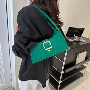 Detail of green felt shoulder bag featuring quilted texture and gold horseshoe buckle