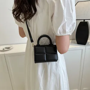 Detail of a black geometric quilted PU leather mini bag with gold-tone hardware and top handle