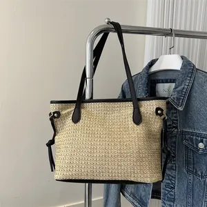 Dettaglio della borsa in paglia con trama intrecciata e manici in pelle sintetica nera