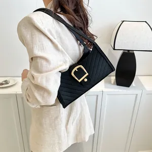 Detailed view of black felt shoulder bag with quilted texture and gold horseshoe buckle