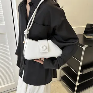 Detailed view of a white minimalist underarm bag with knot strap and round buckle detail