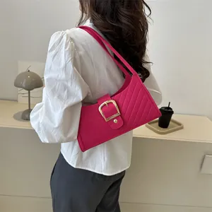 Close-up of bright pink felt shoulder bag featuring diagonal quilting and a large gold clasp