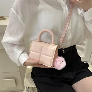 Detailed view of pink quilted mini handbag featuring a cute plush puff ball charm