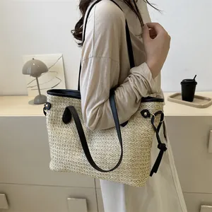 Borsa tote in paglia intrecciata beige con manici in pelle nera in un interno moderno