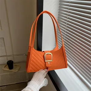 Detailed view of orange felt handbag featuring diagonal quilting and a gold square buckle
