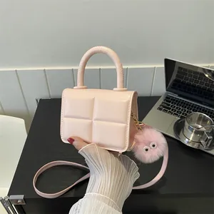 Detailed shot of a pink quilted mini bag with a playful plush charm and sleek leather strap
