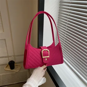 Close-up of hot pink felt bag featuring quilted texture and large matte gold buckle