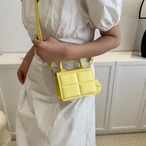 Minimalist yellow quilted crossbody bag with stylish faux fur ball charm and top handle