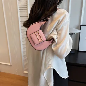 Close-up of pink crescent underarm bag with gold buckle worn on model shoulder
