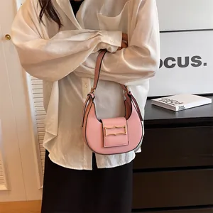 Detail of pink crescent leather shoulder bag with gold clasp shown on a model