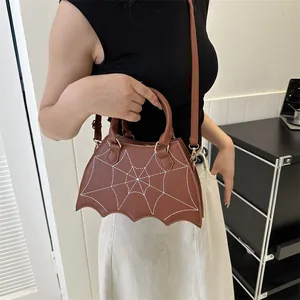 Brown faux leather crossbody bag with white spider web embroidery and bat wing edges