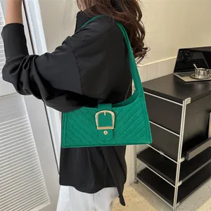 Green quilted felt shoulder bag with large gold buckle in a modern office setting