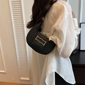 Detail of minimalist black crescent bag with gold buckle styled on a white shirt