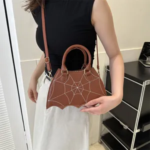 Brown bat-shaped PU handbag with white spiderweb embroidery worn by a model