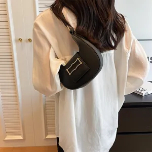 Detail of black crescent shoulder bag featuring a wave-shaped gold metal buckle