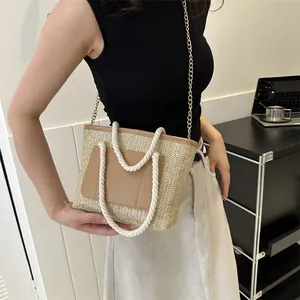 Détail du sac cabas en paille tissée avec poche avant en cuir et poignées en corde