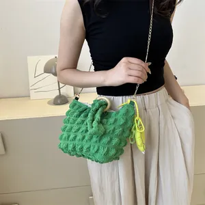 Detail of green popcorn texture handbag featuring golden chain strap and yellow charm