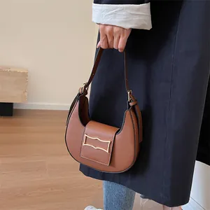 Close-up of brown crescent hobo bag featuring a gold metal buckle and leather strap