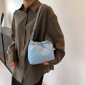 Hellblaue Stepp-Eimertasche mit silberner Kette, präsentiert von einem Model im Alltag