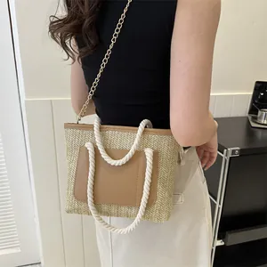Détail du sac en paille tissée montrant la texture en V et la bandoulière en chaîne dorée