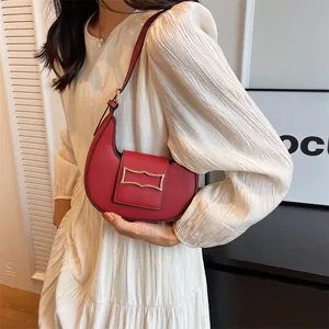 Detailed view of red crescent shoulder bag with gold hardware on a white dress model