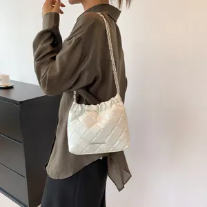 Detail der weißen gesteppten Beuteltasche mit Kettenriemen und Kordelzugverschluss