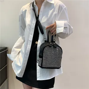 Detail eines schwarzen Mini-Rucksacks mit silbernen Strasssteinen und Trägern