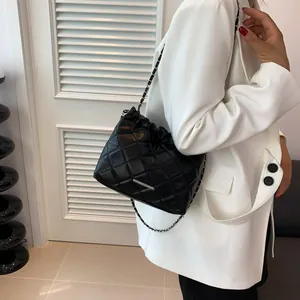 Detail einer schwarzen Stepp-Eimertasche mit Silberleiste und Kettenriemen am Modell