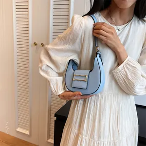 Detail of light blue hobo bag with gold hardware worn by a model in a white dress