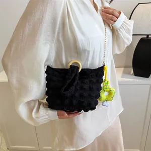 Detail of black bubble texture bag with wooden handle and yellow flower charm decoration