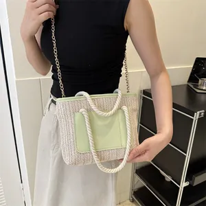 Détail du sac cabas en paille tissée avec patch en cuir vert clair et chaîne dorée