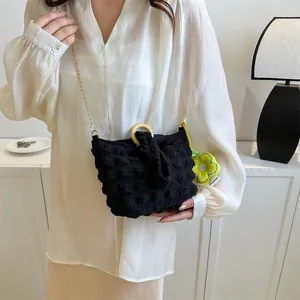 Detail of black popcorn texture fabric bag with wooden ring handle and gold chain strap